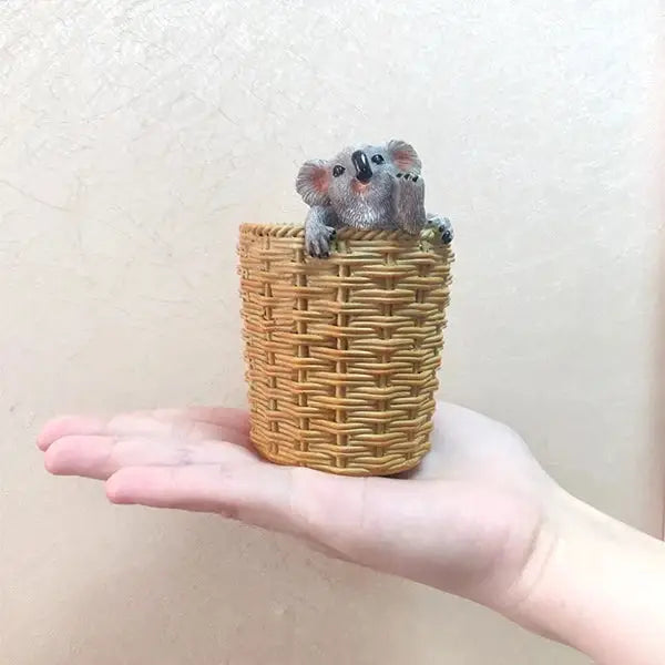 a hand holding a miniature mouse in a wicker basket