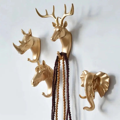 a group of three gold deer head hooks on a wall