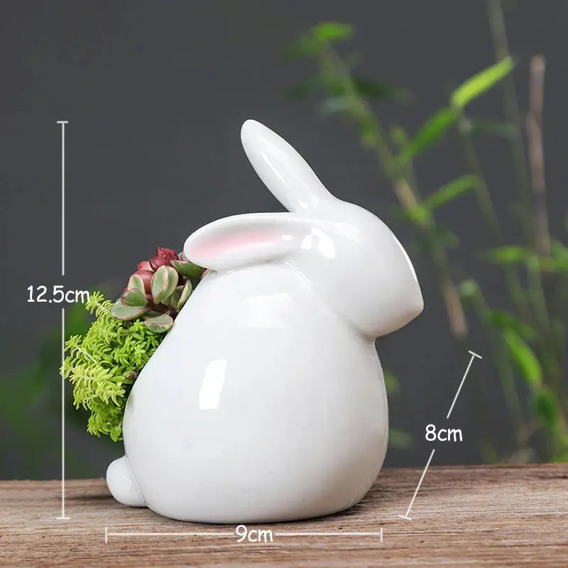 a white bunny shaped vase with succulents and a succulent plant