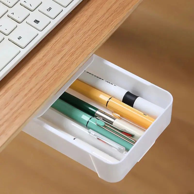 a drawer with pens, pencils, and a keyboard