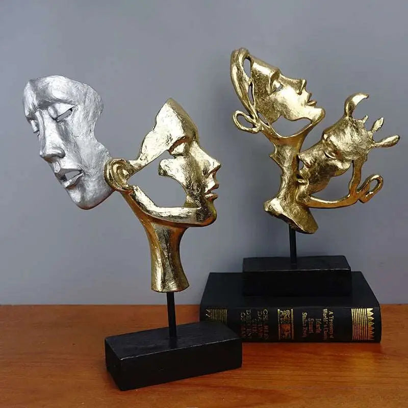 a couple of gold and silver sculptures sitting on top of a wooden table