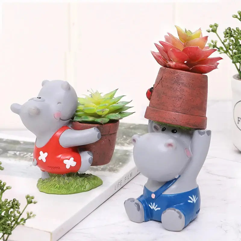 a small statue of a hippo holding a potted plant