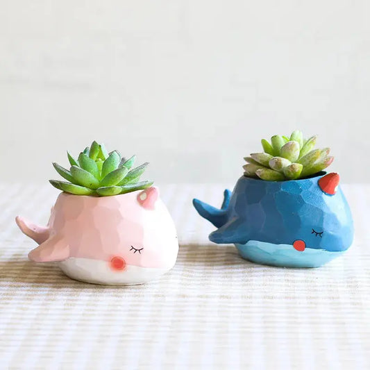 two ceramic pots with plants in them on a table