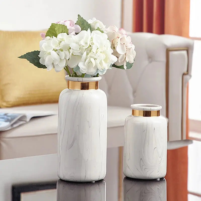 two white vases with flowers in them on a table