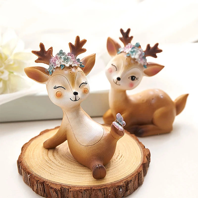 a couple of deer figurines sitting on top of a wooden slice