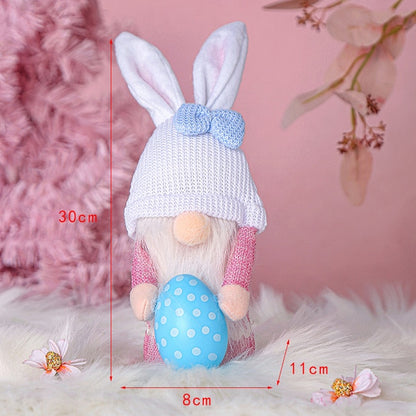 a stuffed rabbit holding a blue egg
