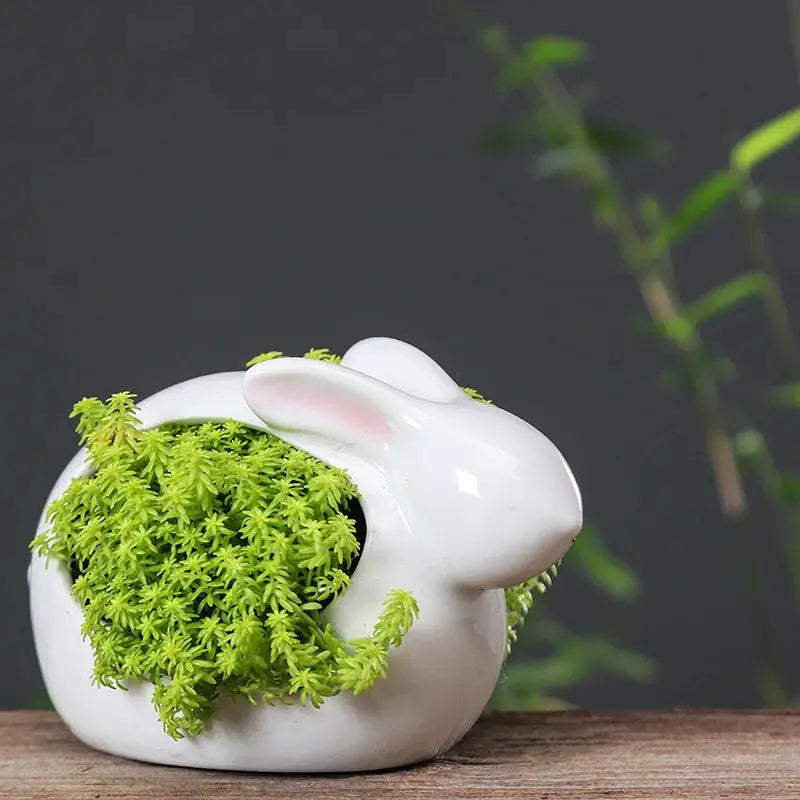 a white ceramic rabbit with moss in its mouth
