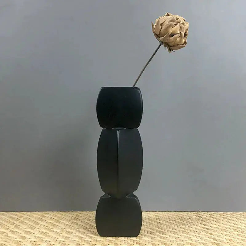 a black vase with a single flower in it