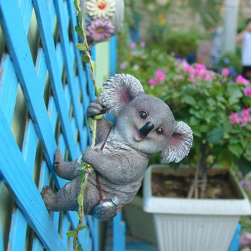a small stuffed koala hanging from a blue fence