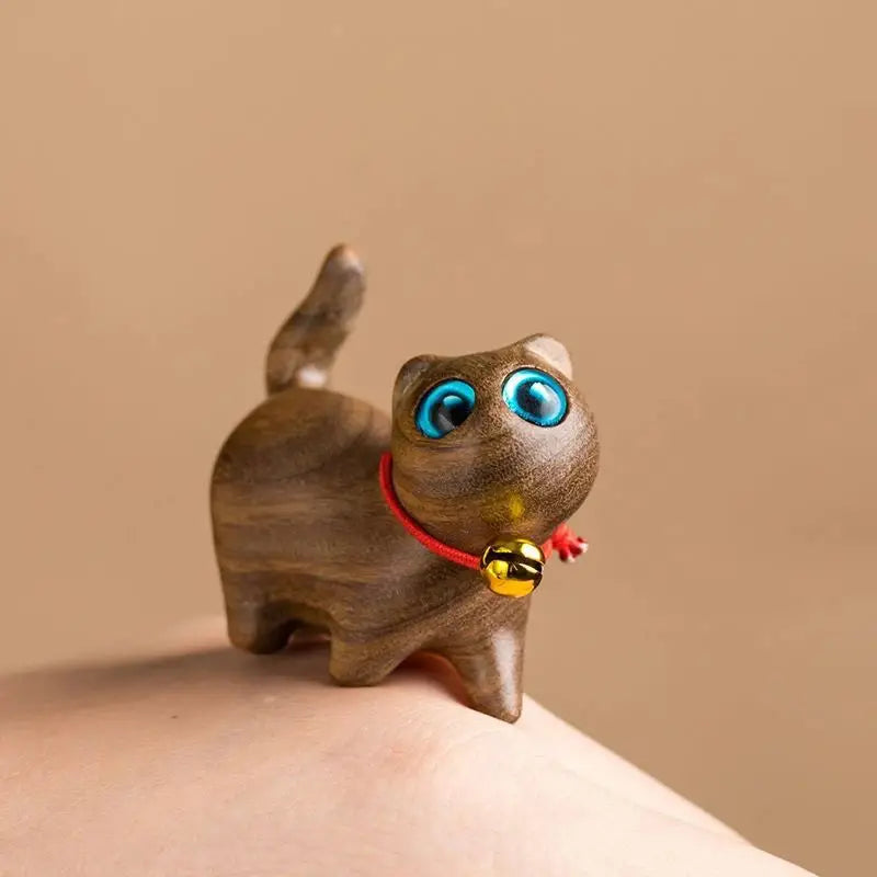 a small wooden cat figurine sitting on someone's hand