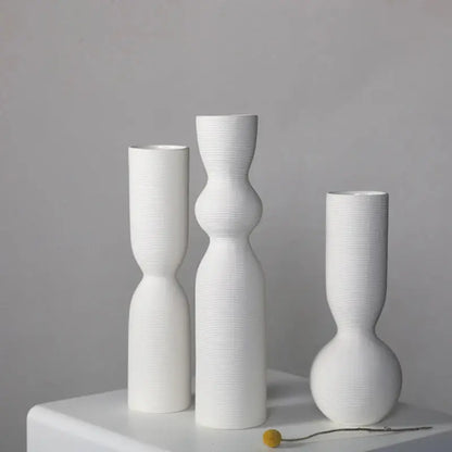 three white vases sitting on top of a white table