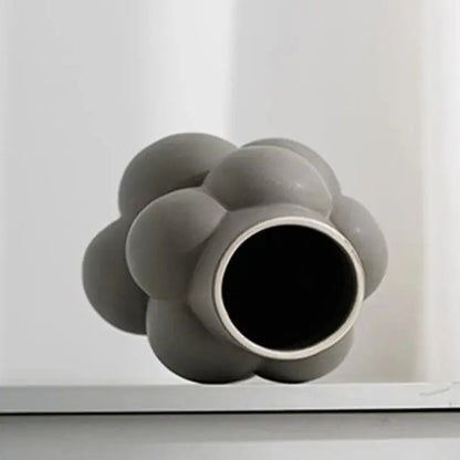 a gray vase sitting on top of a white shelf