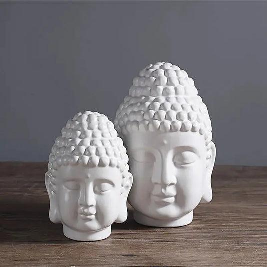a couple of white buddha heads sitting on top of a wooden table