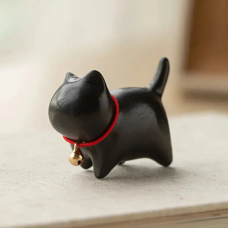a small black cat figurine with a bell around its neck
