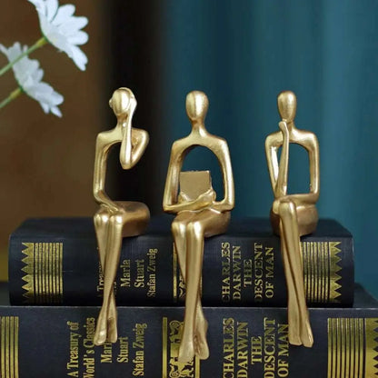 a couple of gold figurines sitting on top of a book