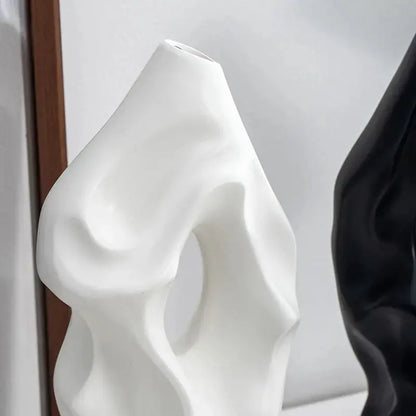 a white vase sitting next to a black vase