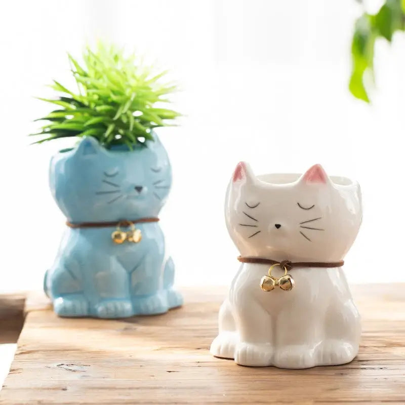 two ceramic cats sitting next to each other on a table