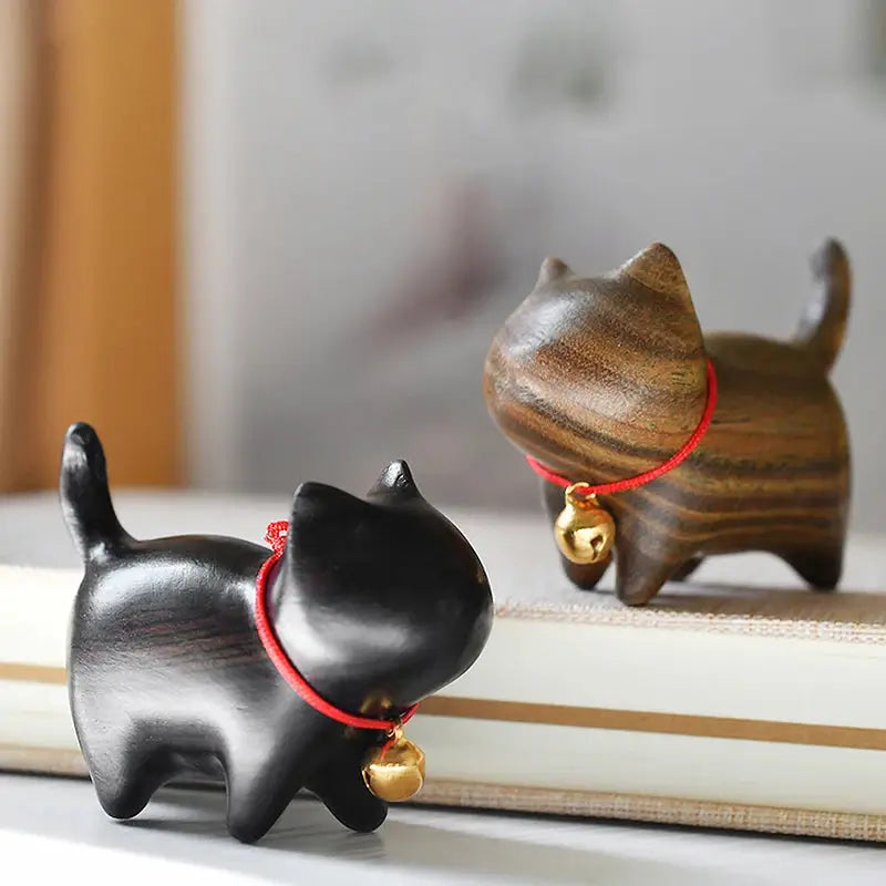 two small wooden cat figurines sitting on top of a book