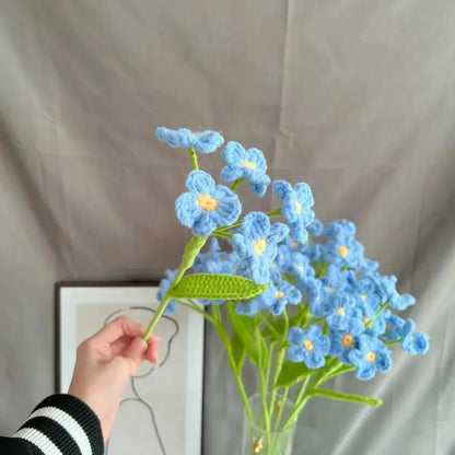 a person is holding a blue flower in a vase