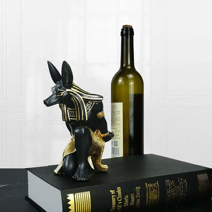 a bottle of wine next to a statue of anub and a book