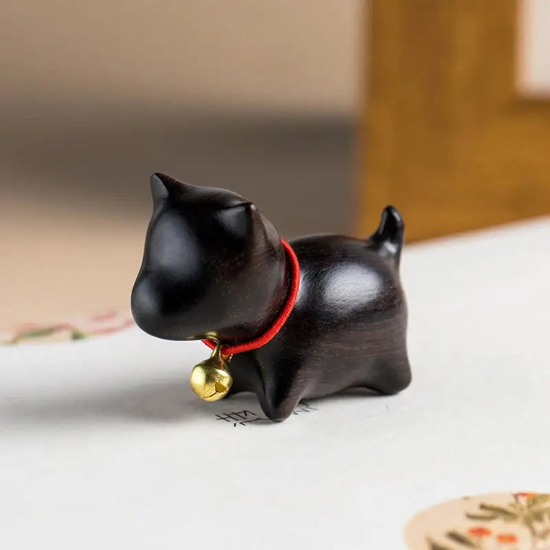 a black cat figurine with a bell around its neck