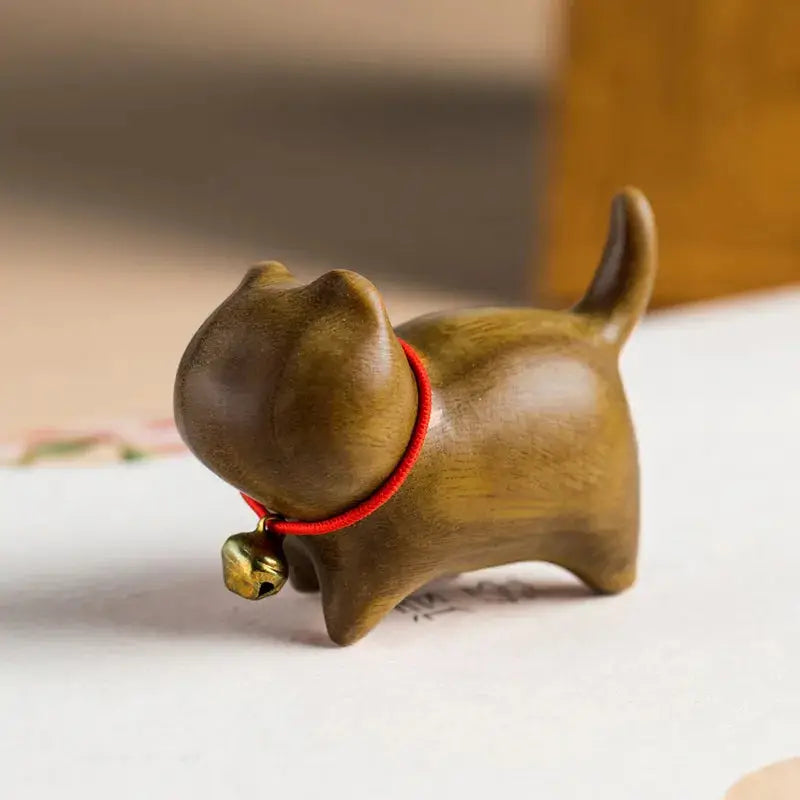 a small wooden dog figurine with a bell around its neck