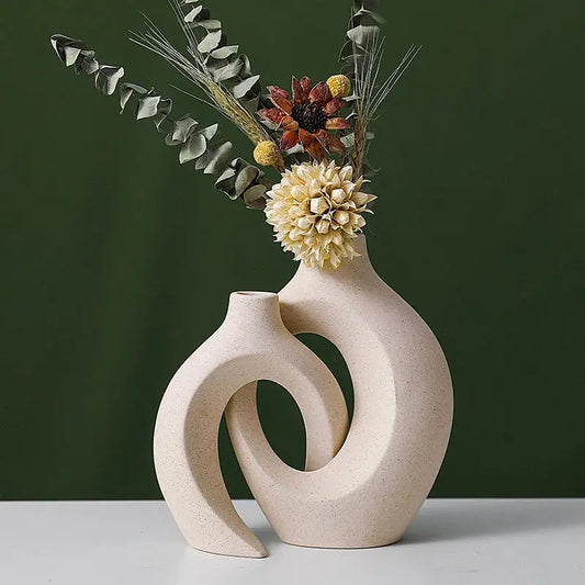 a white vase with flowers in it on a table
