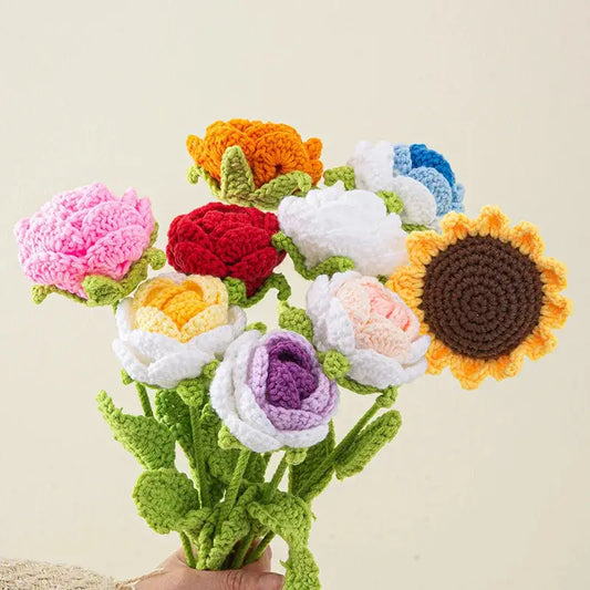 a hand holding a crocheted bouquet of flowers