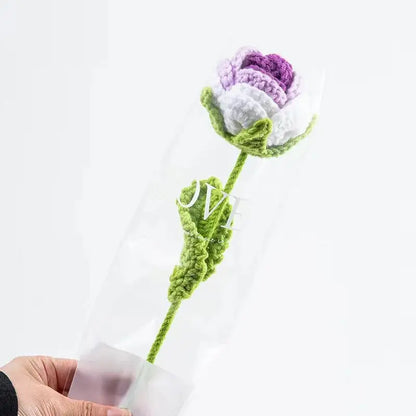 a hand holding a crocheted flower in a plastic bag