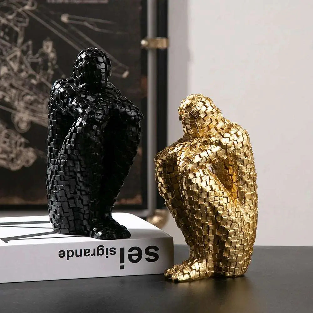 a couple of gold and black sculptures sitting on top of a table