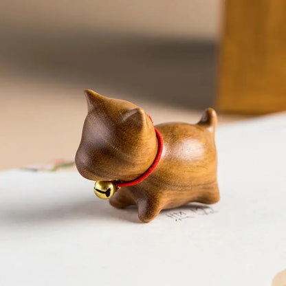 a small wooden cat figurine with a bell around its neck