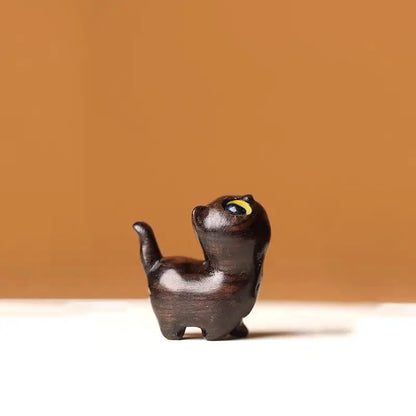 a black cat figurine with a yellow eye