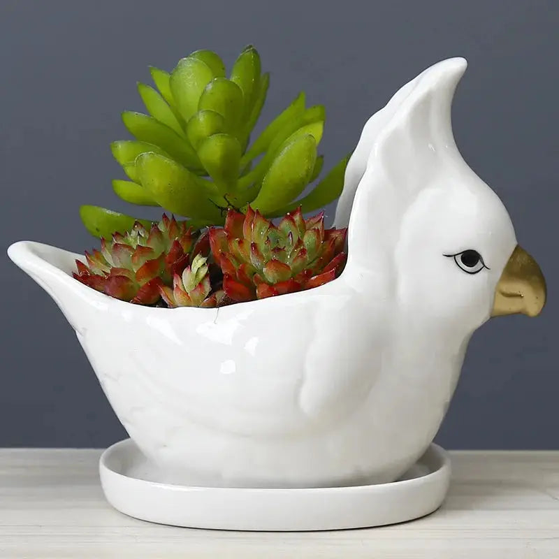a white ceramic bird planter with succulents in it