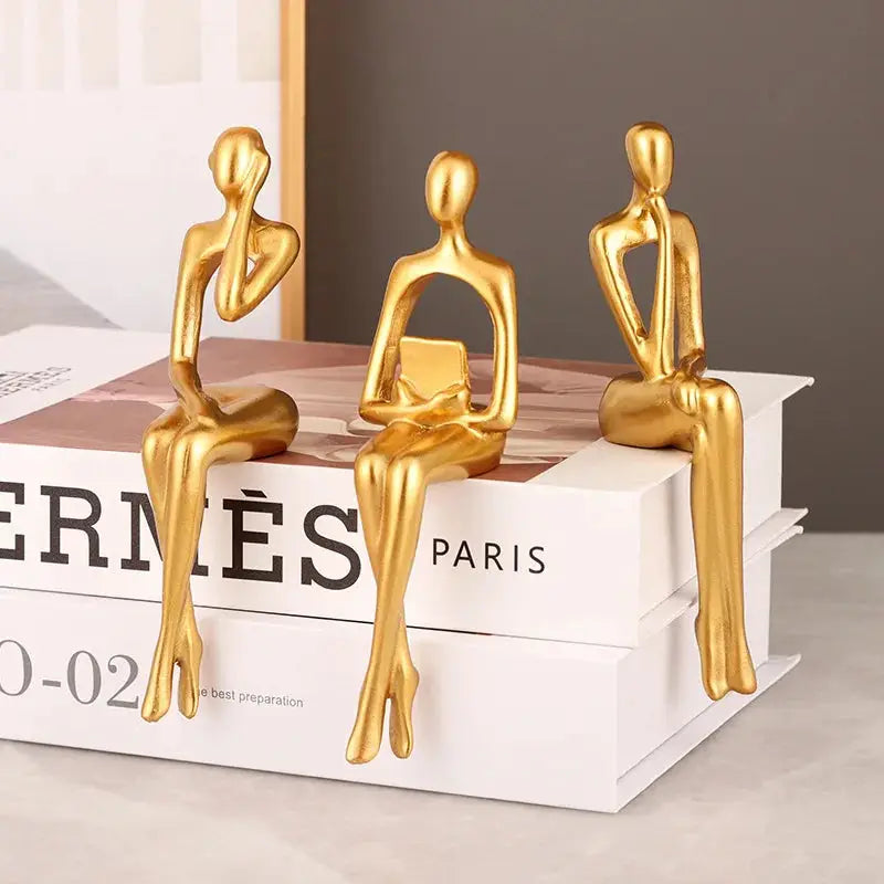 three gold figurines sitting on top of a book