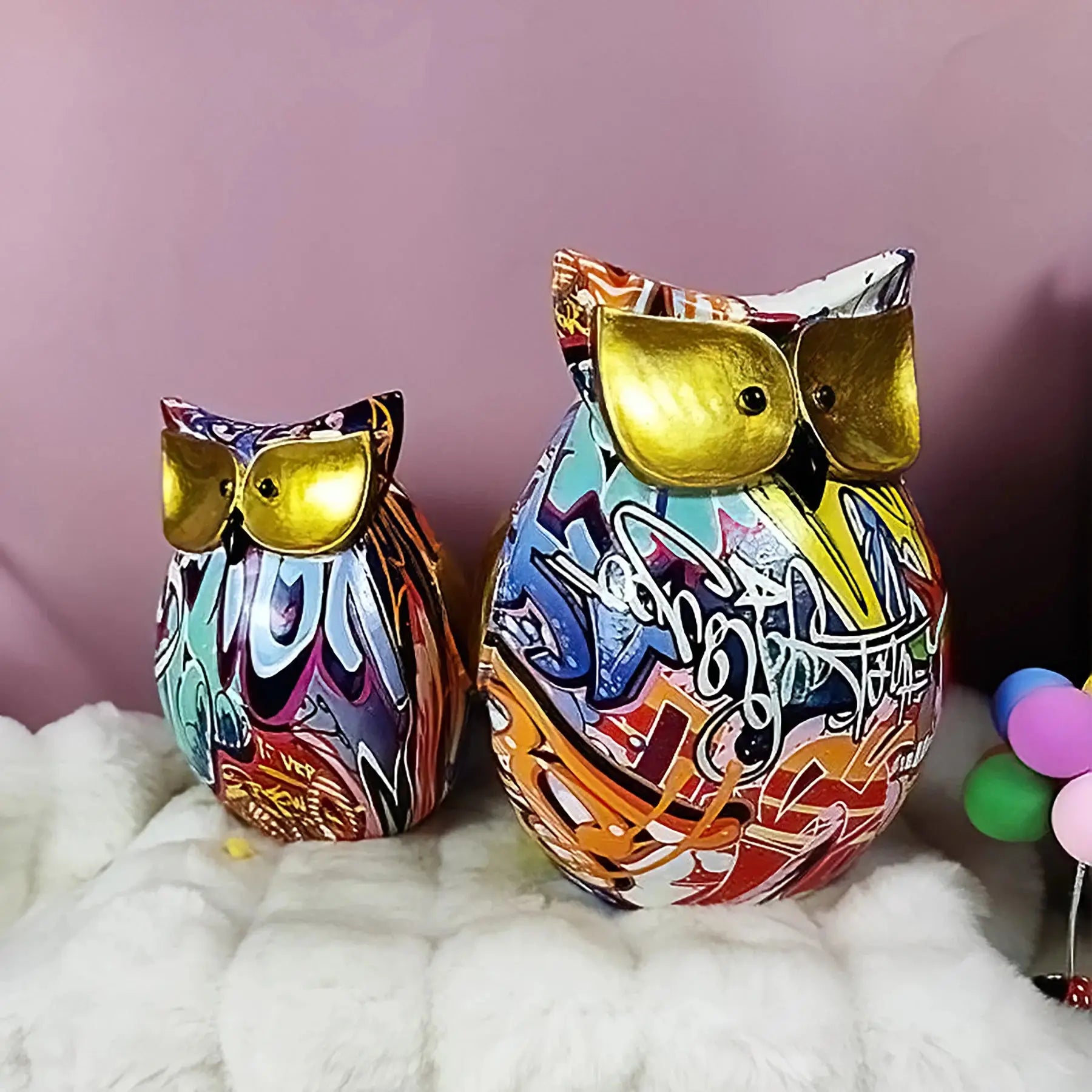 a couple of colorful owls sitting on top of a bed