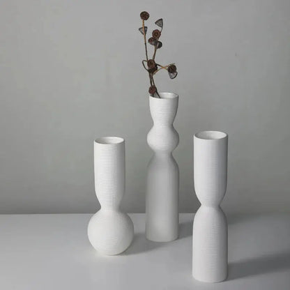 three white vases with flowers in them on a table