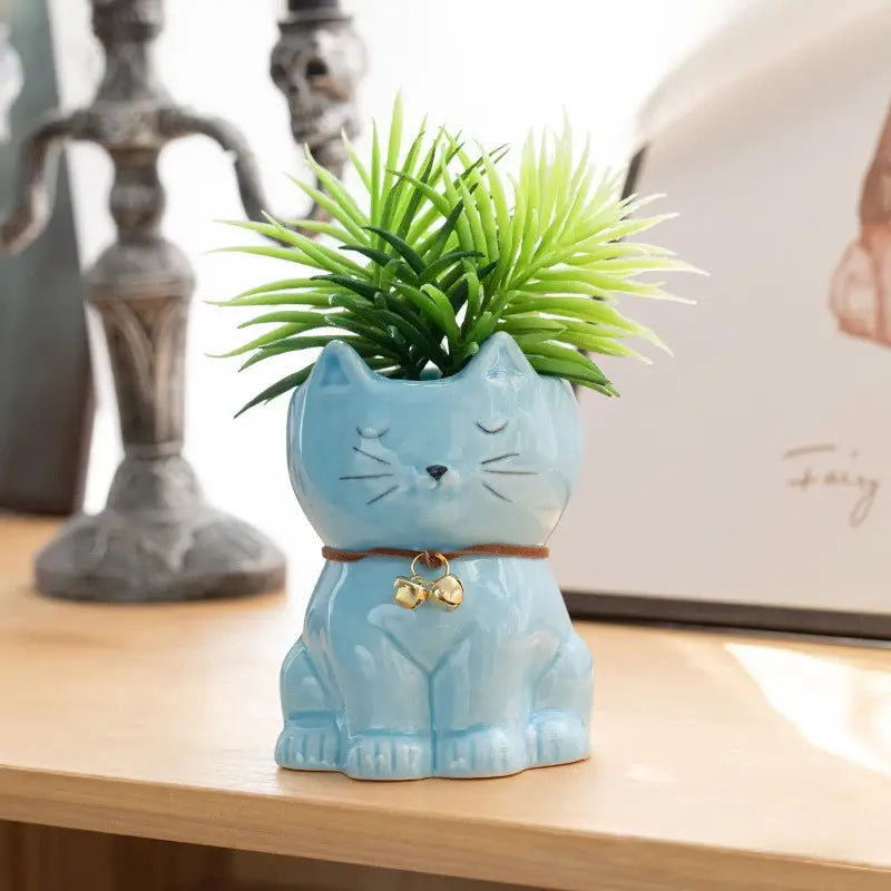 a blue ceramic cat planter with a green plant in it