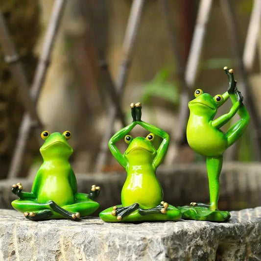 a group of three green frogs sitting on top of a rock