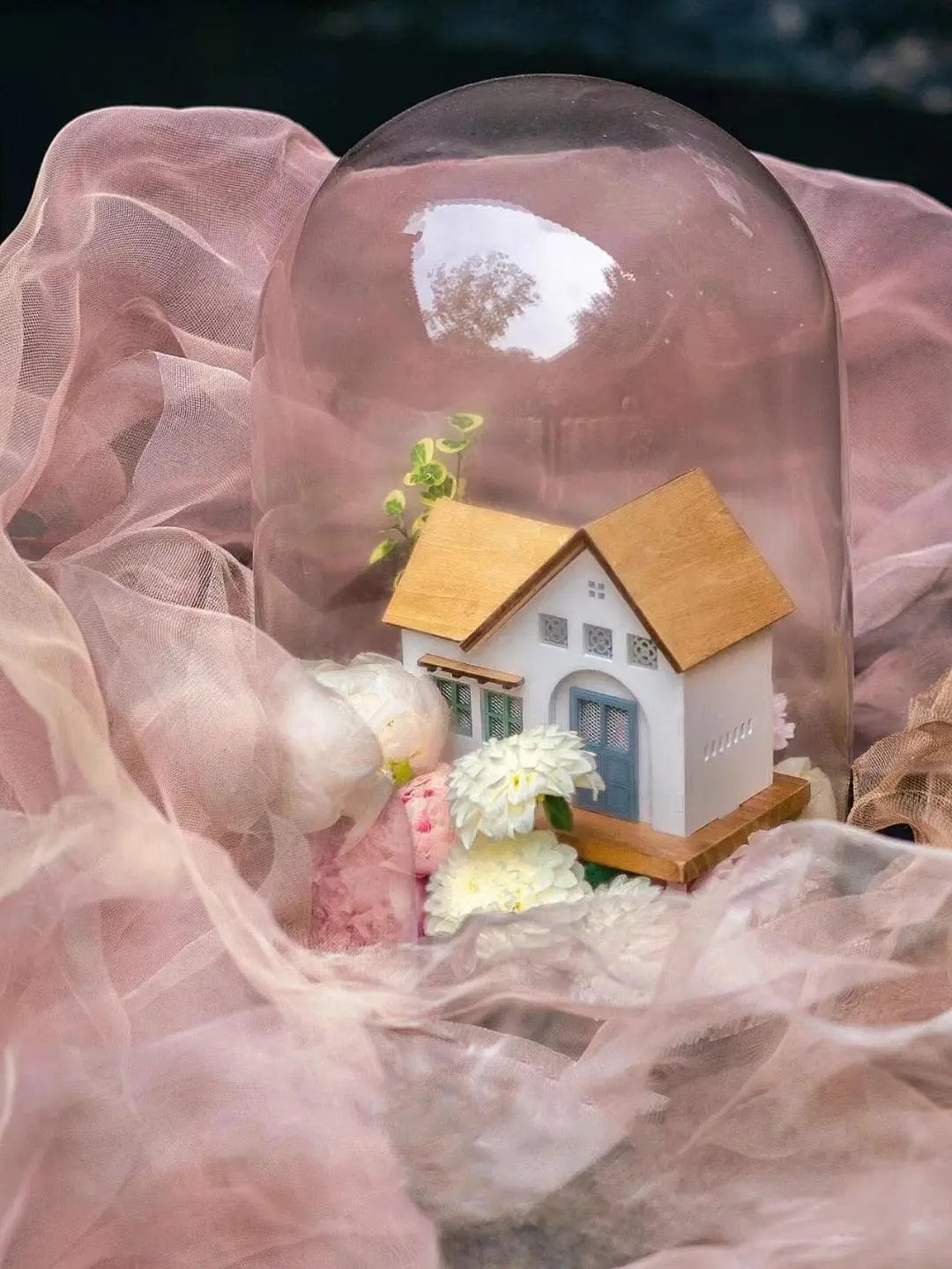 a house in a glass dome with flowers inside