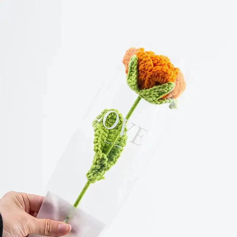 a person holding a crocheted flower in their hand