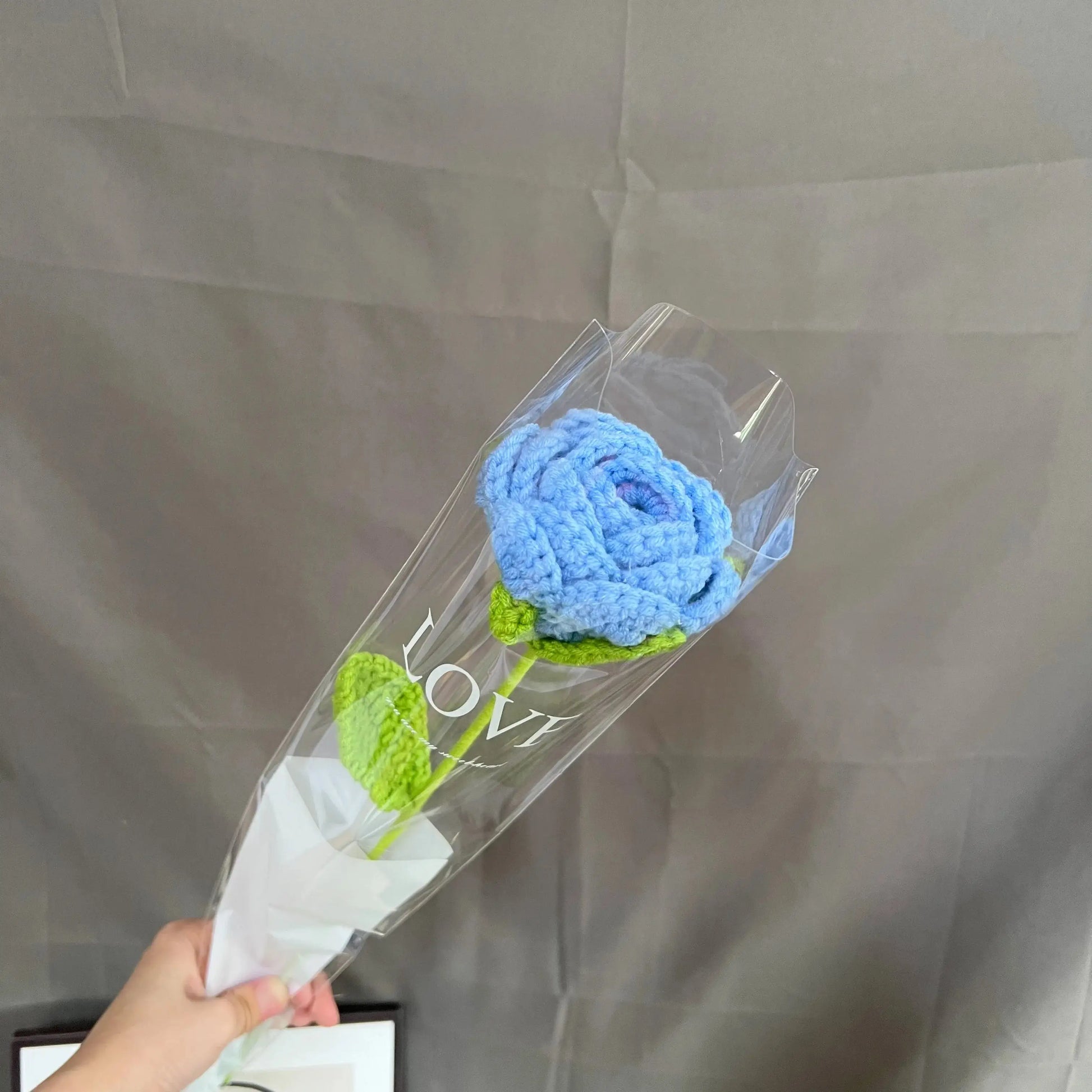 a person holding a clear vase with a blue flower in it