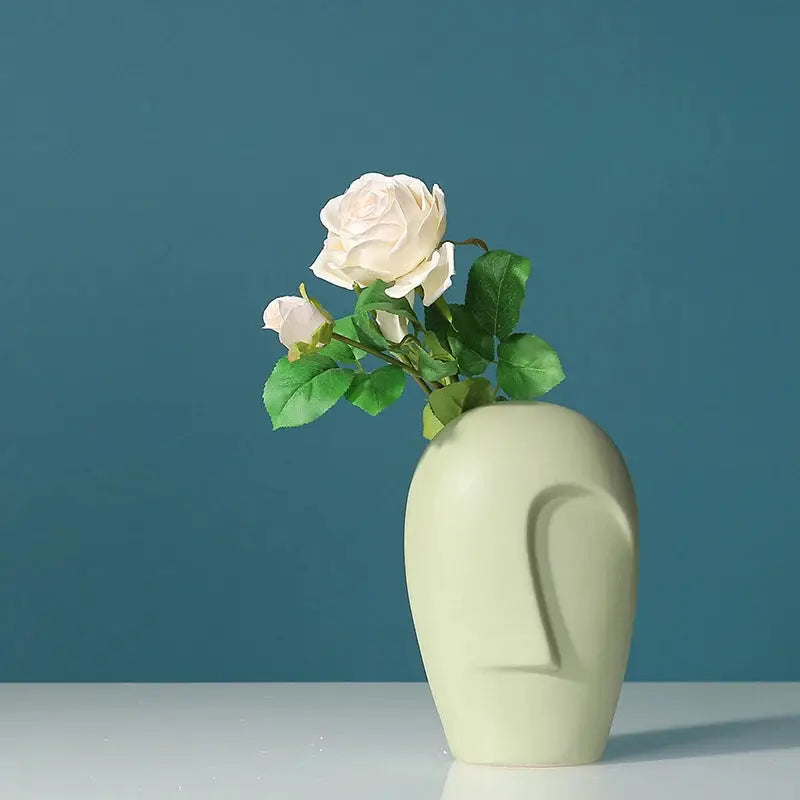 a white vase with a white rose in it