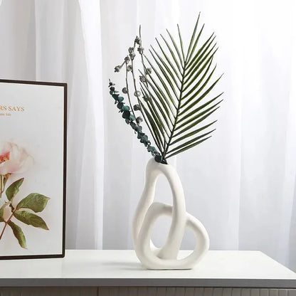 a white vase with a plant in it next to a card