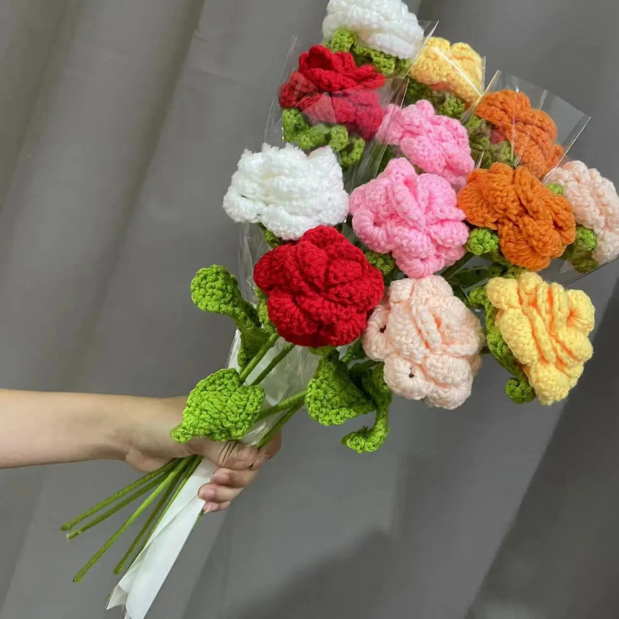 a person holding a bouquet of crocheted flowers
