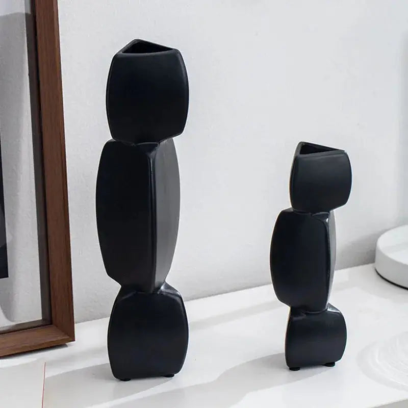 a couple of black vases sitting on top of a white counter