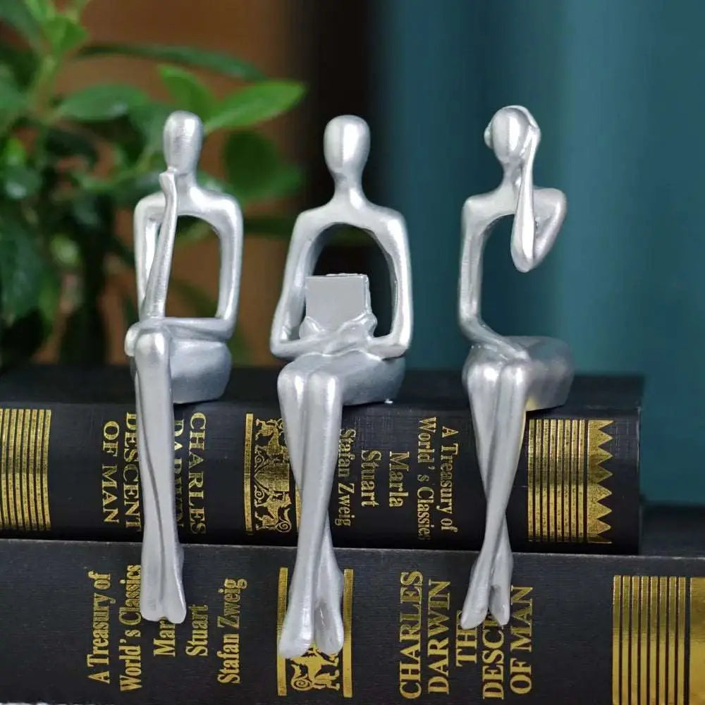 a couple of silver figurines sitting on top of a stack of books