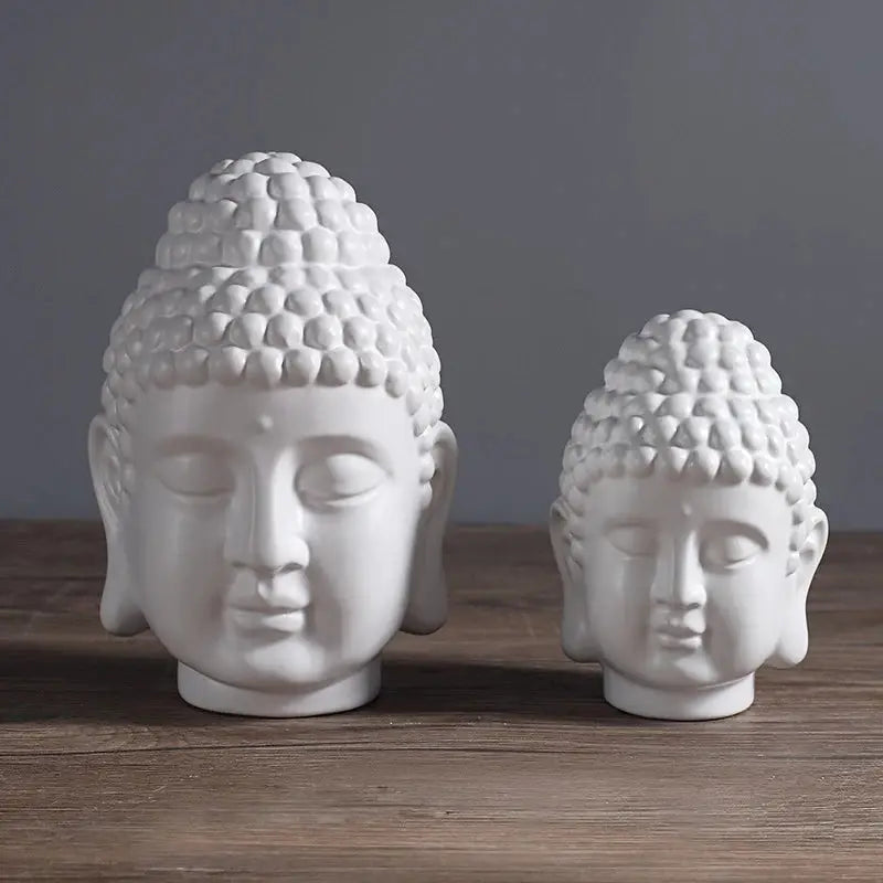 a couple of white buddha heads sitting on top of a wooden table