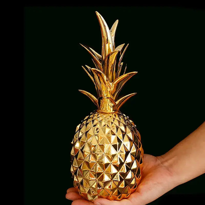 a hand holding a gold pineapple shaped object