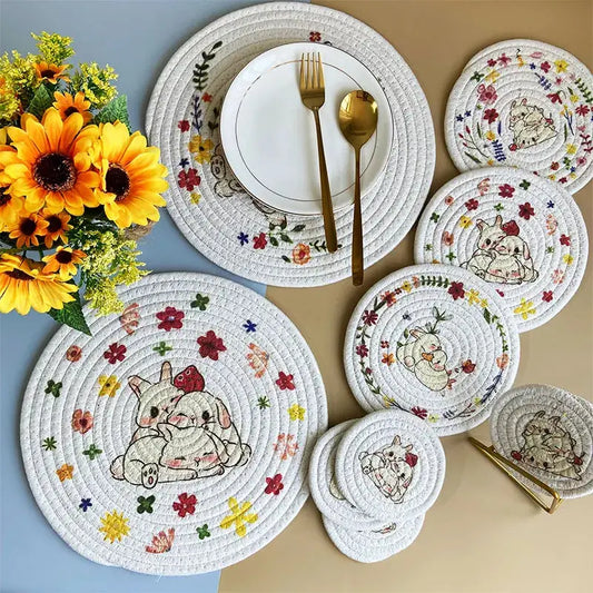 a table set with place mats, plates, and a vase of sunflowers