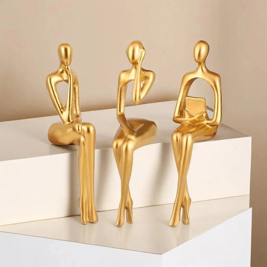 a group of three gold figurines sitting on top of a table